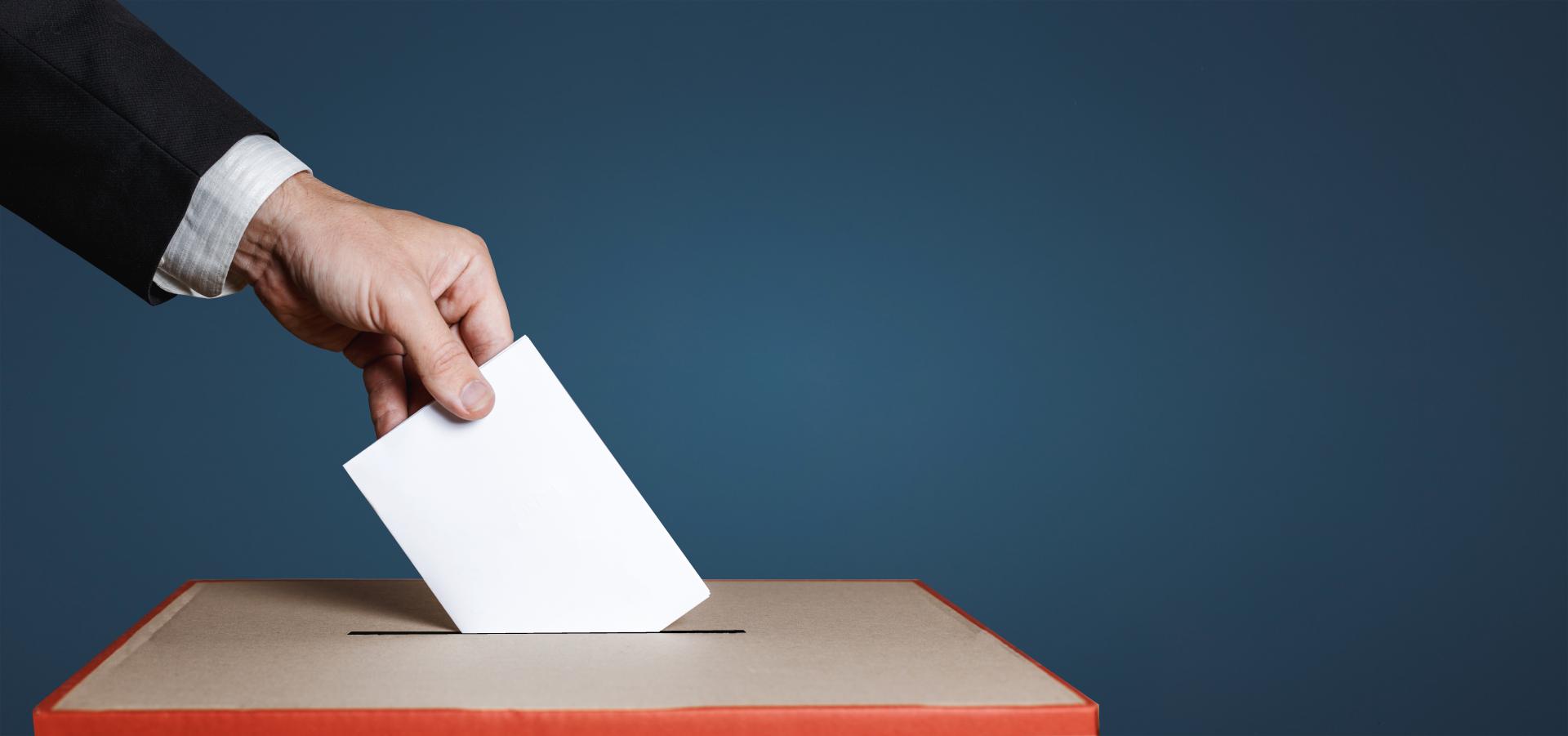 Main mettant un bulletin dans une urne électorale 