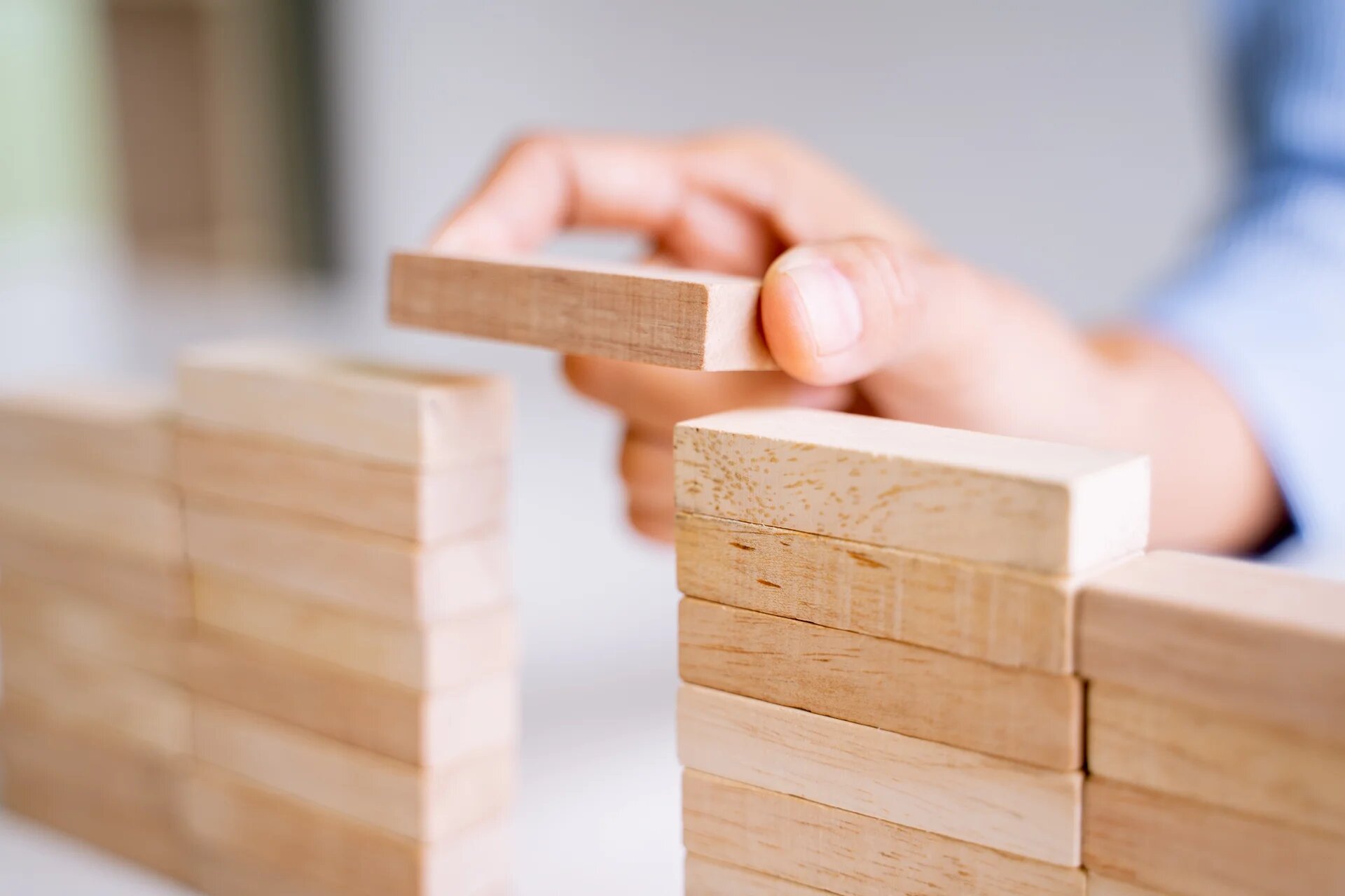 Une main qui vient poser un bout de bois de son jeu de construction pour terminer une porte